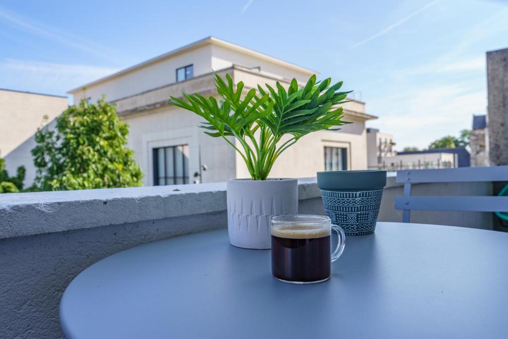 eine Tasse Kaffee und eine Topfpflanze auf dem Tisch in der Unterkunft Le Balcon des Arts - PrestiPlace Tours in Tours