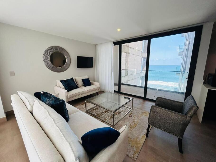 a living room with a white couch and a large window at En Malecón con vista al mar y lago by G P S rentas in Mazatlán