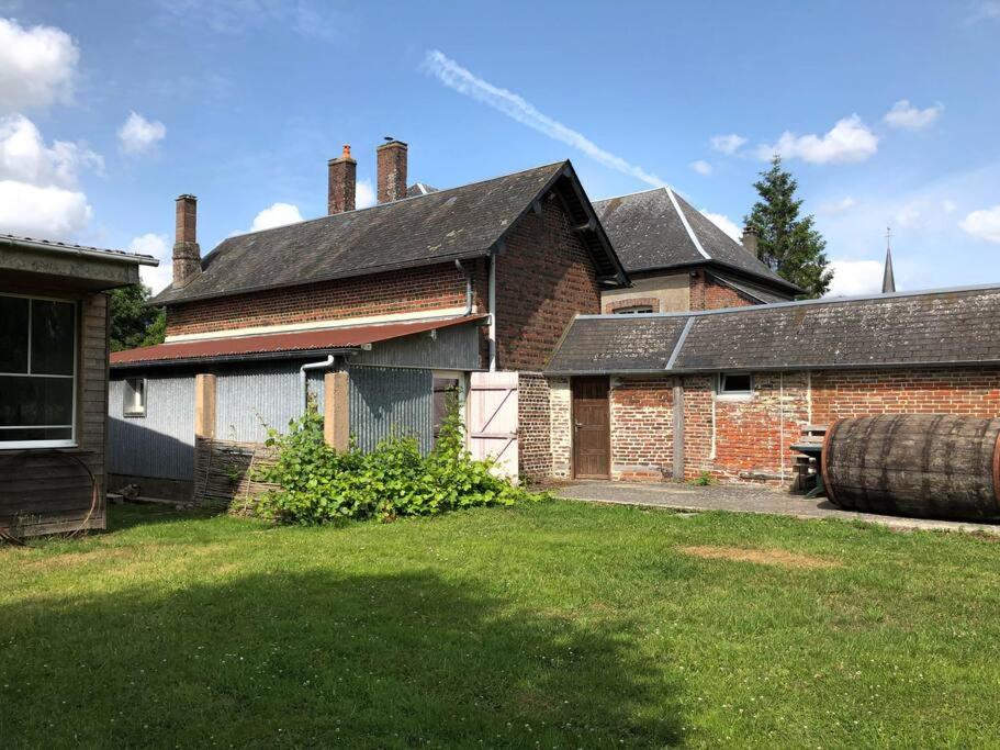una vieja casa de ladrillo con un patio y un barril en Gîte au cœur d'une résidence d'artiste en Saint-Aubin-de-Bonneval