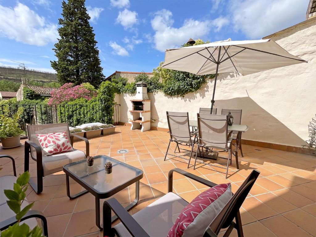 un patio con mesa, sillas y sombrilla en Apartamentos Puente La Reina, en Puente la Reina