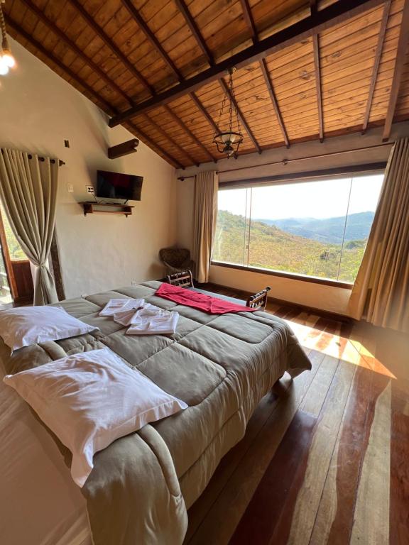 1 dormitorio con 1 cama grande y ventana grande en Chalés Vista das Montanhas en Lavras Novas