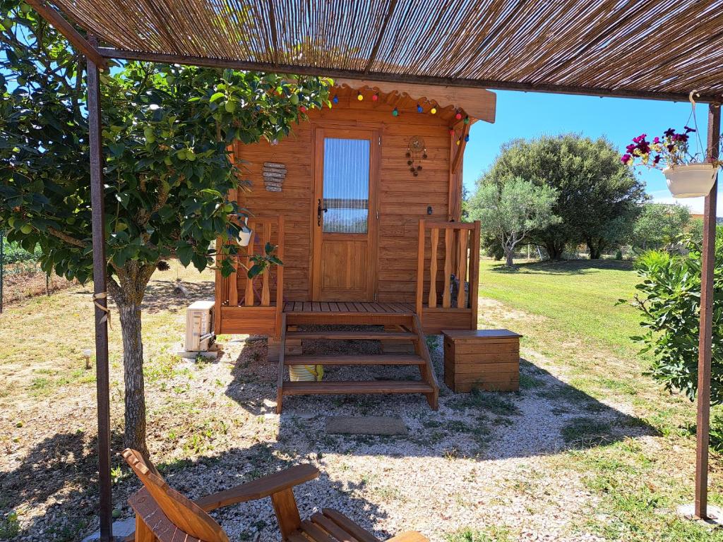 eine Holzhütte mit einer Bank und einem Regenschirm in der Unterkunft Roulotte en bois in Fuveau