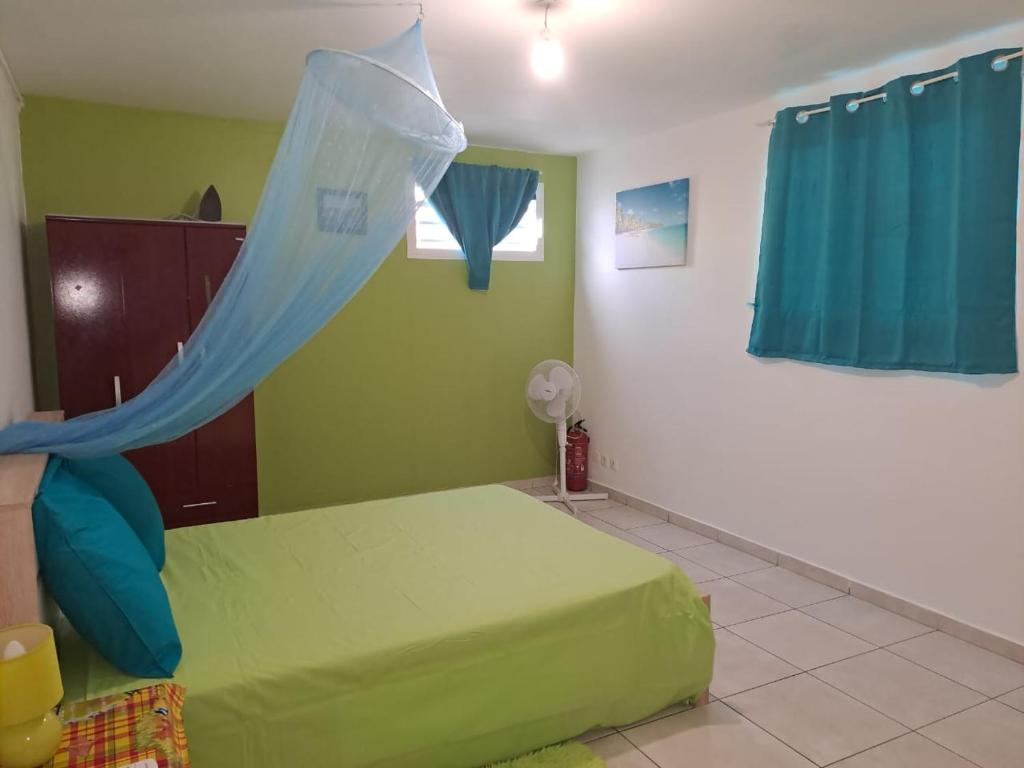 Schlafzimmer mit einem grünen Bett und einem Moskitonetz in der Unterkunft La Casa Binecha avec Jacuzzi in Baillif