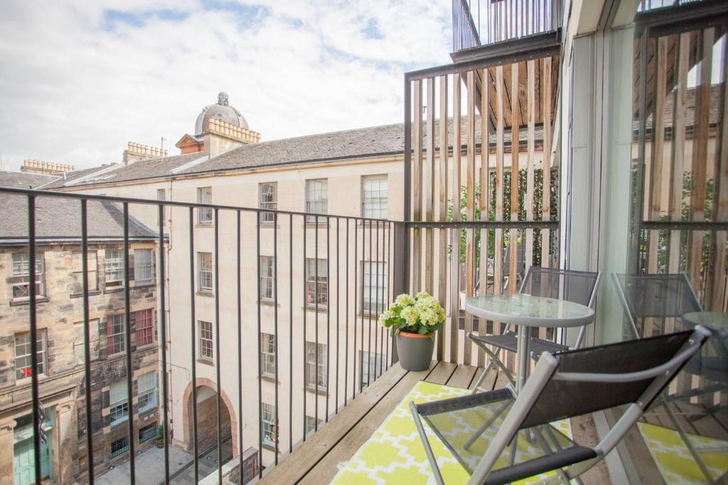a balcony with a table and chairs on a building at 1 Bedroom Flat in the Heart of Merchant City in Glasgow