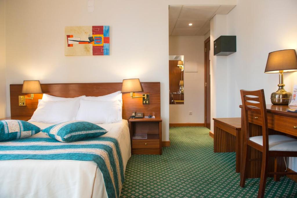 um quarto de hotel com uma cama e uma escrivaninha em Hotel Eurosol Gouveia em Gouveia