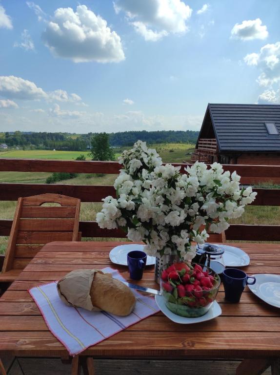 a wooden table with a plate of bread and flowers at Jotwingia - Domki z Widokiem in Stare Juchy