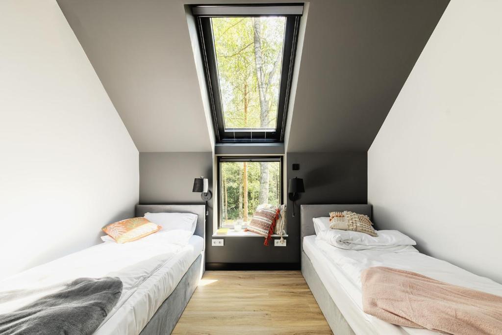 two beds in a room with two windows at Między Drzewami in Olsztyn