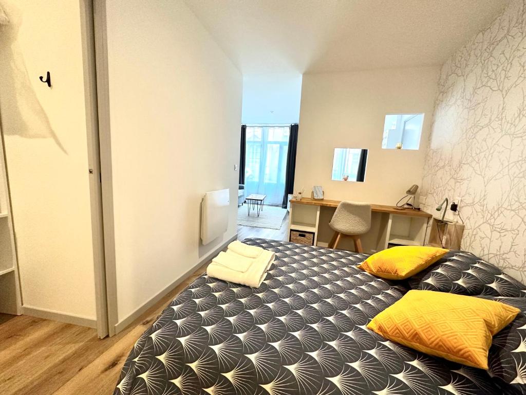 Bel appartement en plein centre ville في ليموج: غرفة نوم مع سرير مع وسائد صفراء ومكتب