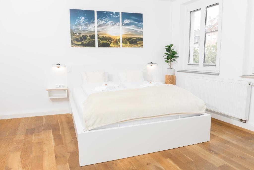 een wit bed in een witte kamer met ramen bij HEIMATEL - City Centre Studio in Ravensburg