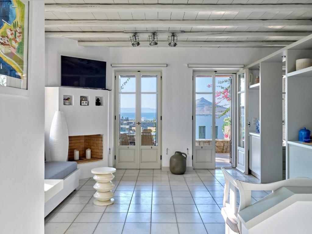 a living room with white walls and white floors and windows at Myrto's House seaview of Naxos in Isterni