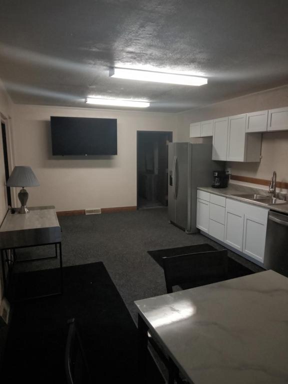 a kitchen with white cabinets and a tv on the wall at E. Michigan Walk Up Furnished 2 Bedroom APT in Lansing