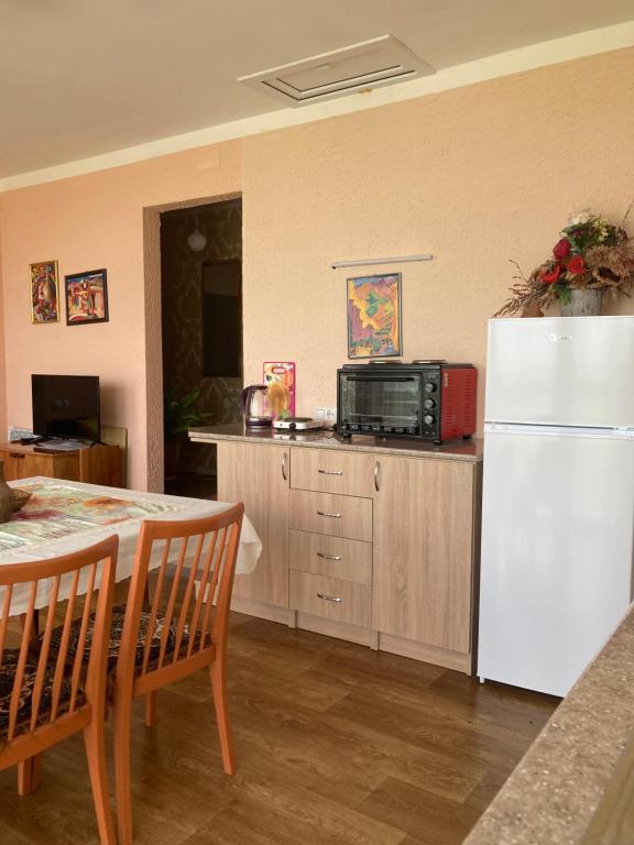 a kitchen with a table and a white refrigerator at Гостевой дом с панорамными окнами in Gyumri