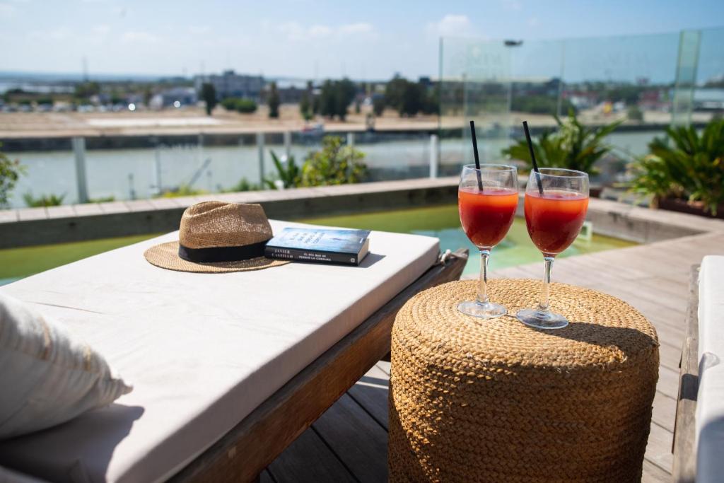 twee glazen wijn en een hoed op een balkon bij Apartamentos Nueva Ribera in El Puerto de Santa María