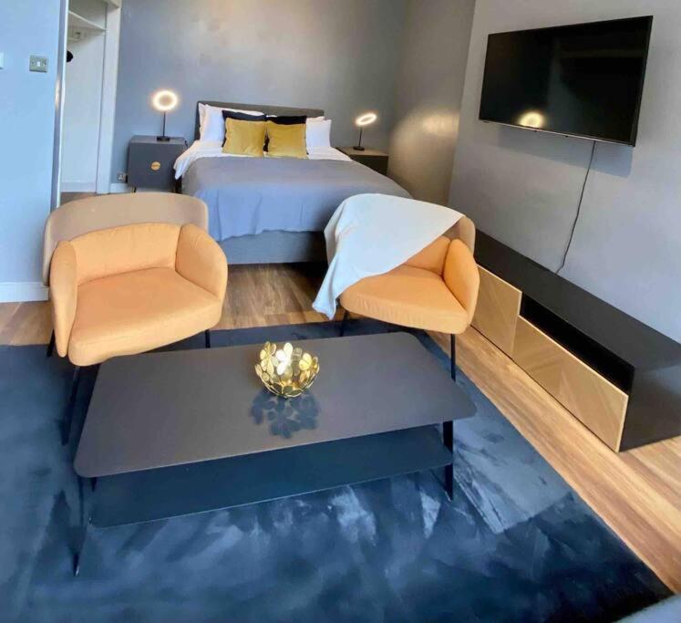 um quarto com uma cama e duas cadeiras e uma televisão em Stylish Studio near Regents Park n6 em Londres