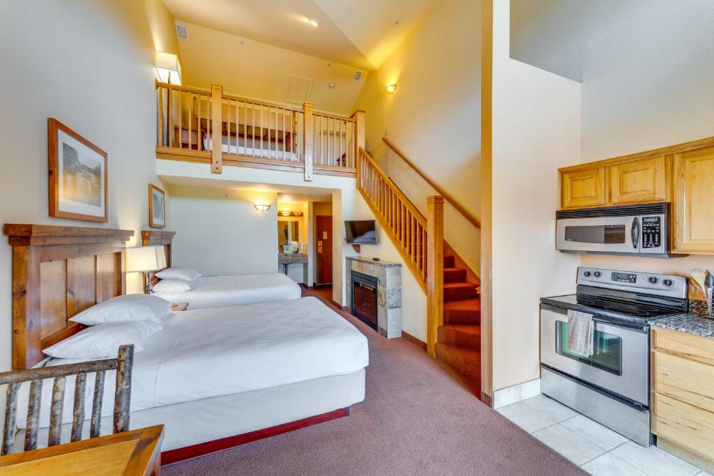 a bedroom with two beds and a kitchen with a staircase at Wisconsin Dells Condo with Pool and Resort Amenities! in Wisconsin Dells