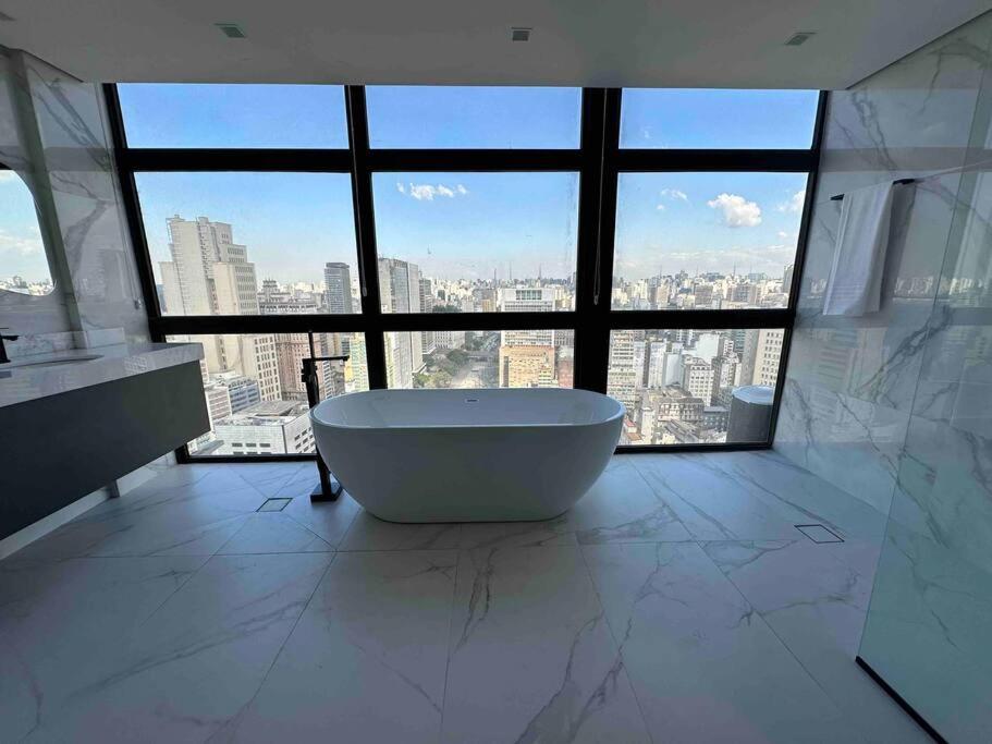 a bathroom with a tub in front of a large window at Sky Loft - Andar 41 in Sao Paulo
