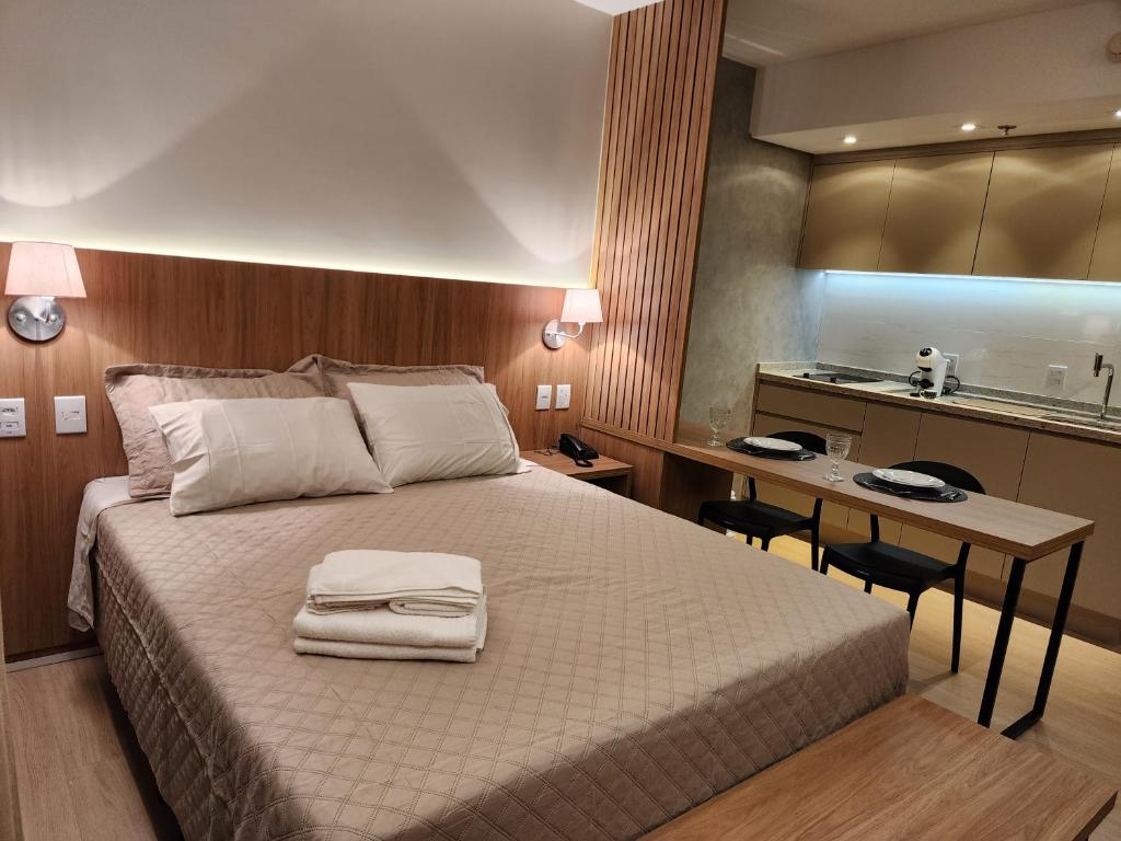 a bedroom with a bed with a desk and a kitchen at Fabuloso Blend Setor Marista in Goiânia