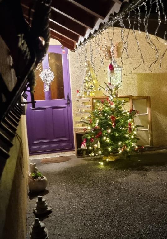un sapin de Noël dans une pièce avec une porte violette dans l'établissement Comme à la maison, chambres au calme, à Verrens-Arvey