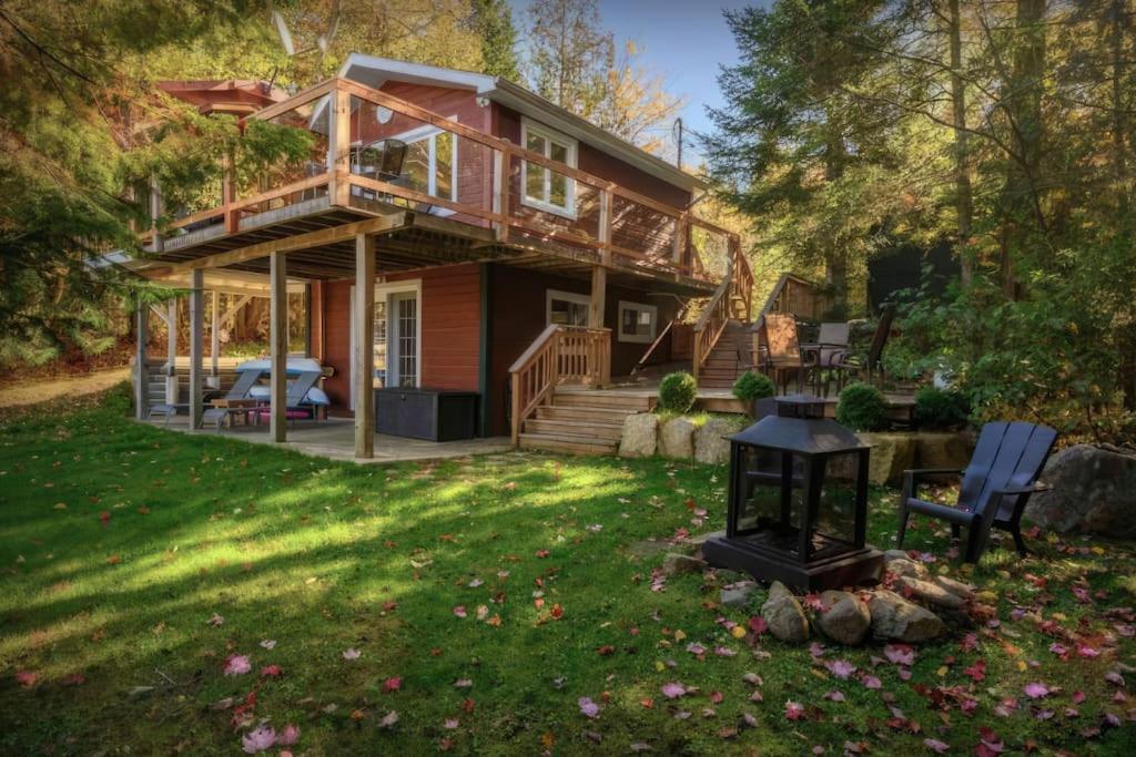 a log home with a deck and a yard at Cabines Niksen in Saint Adolphe D'Howard