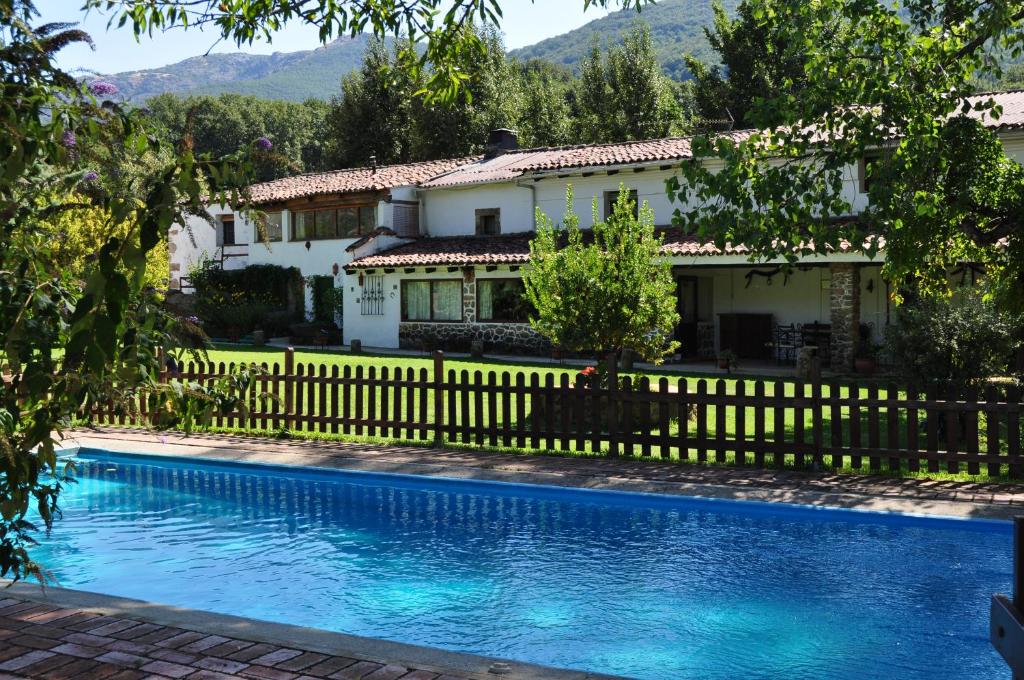 une maison avec une clôture et une piscine dans l'établissement La Casería, à Navaconcejo