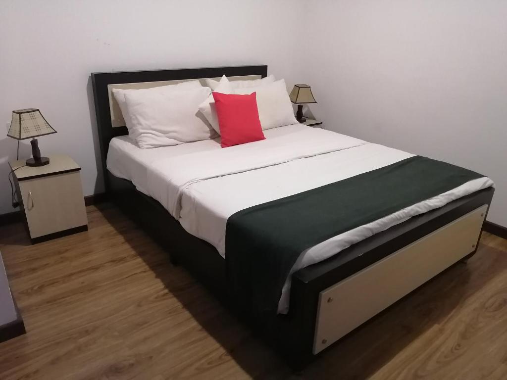 una camera da letto con un grande letto con un cuscino rosso di Roseberry Villa a Nuwara Eliya