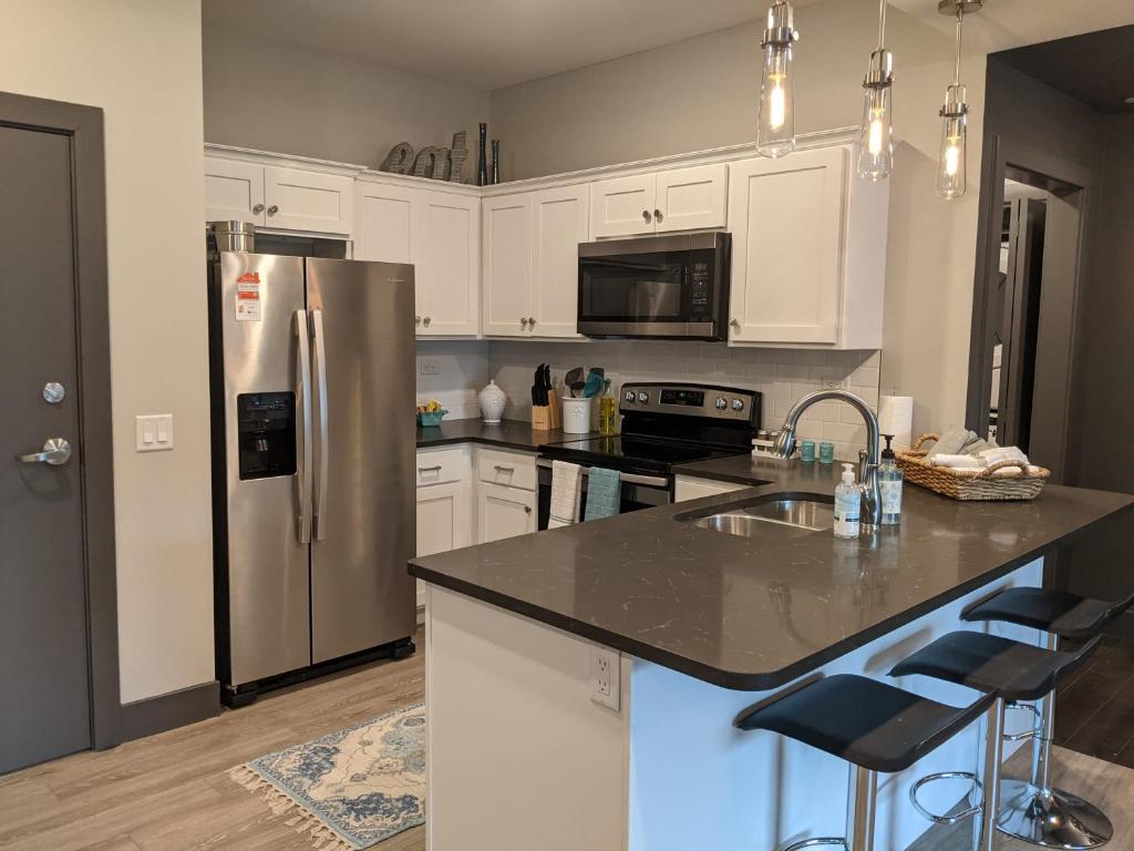 a kitchen with white cabinets and a stainless steel refrigerator at 520 Neil Heart of Downtown Champaign in Champaign