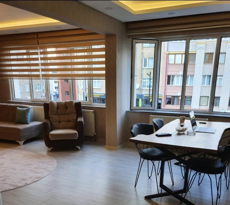 een woonkamer met een tafel, stoelen en ramen bij Sivas Houses Lüks Merkezde Family Suite Home 1 in Sivas