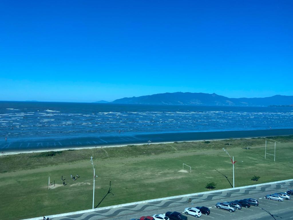 vistas a una playa con coches estacionados junto al agua en Cobertura de frente para o Mar en Caraguatatuba