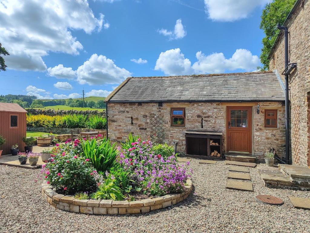 an old stone house with flowers in front of it at Lord Mayors Barn in Alston