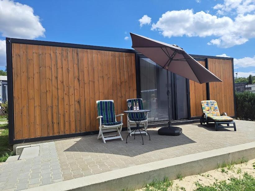 a patio with two chairs and a table and an umbrella at HM - Tinyhouse 1 Deluxe Krombachtalsperre Westerwald in Driedorf