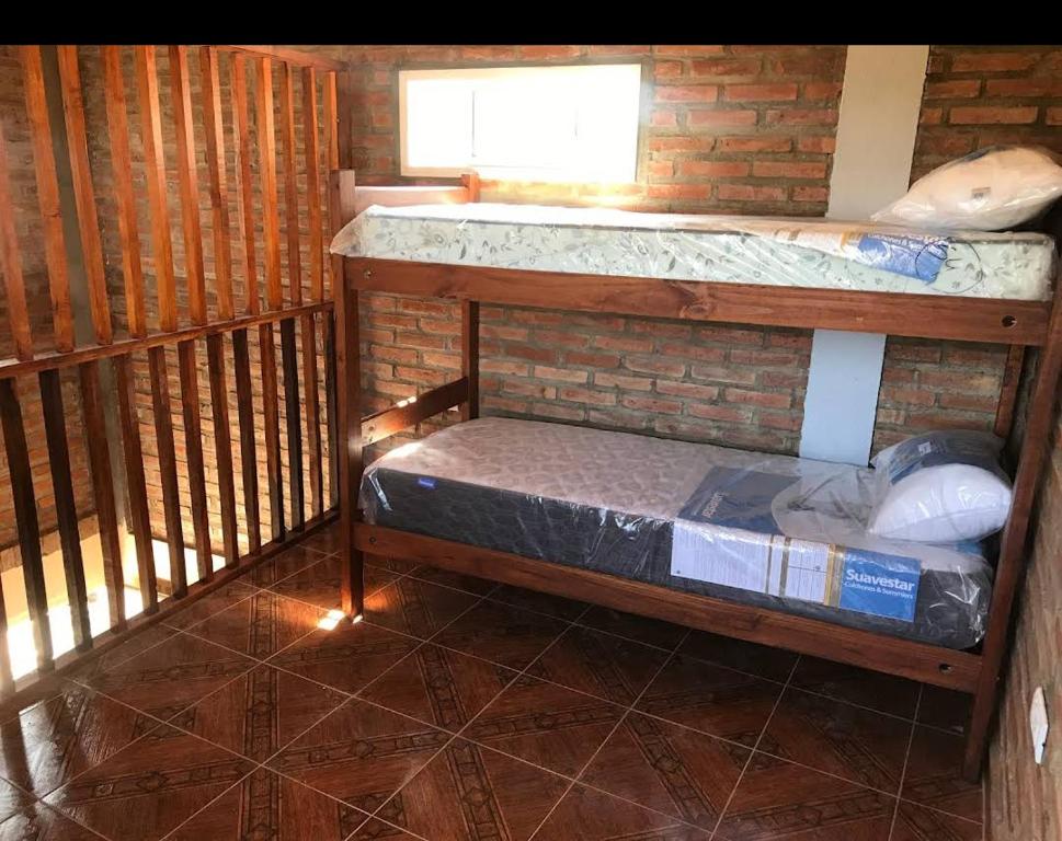 Cabañas Ismiango "Agua de los pajaritos" في Collagasta: سرير بطابقين في غرفة مع جدار من الطوب