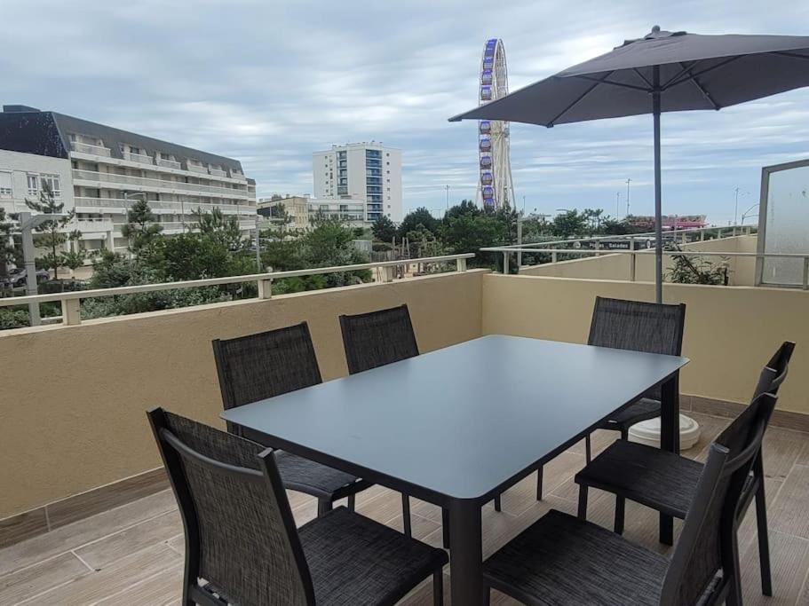 une table et des chaises sur un balcon avec un parasol dans l'établissement Appartement familial terrasse vue mer avec parking, à Berck-sur-Mer