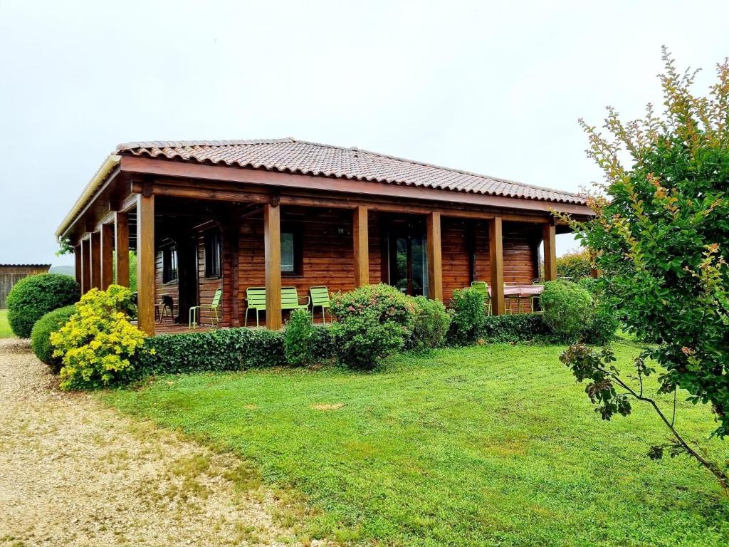 een houten huis met een tuin ervoor bij Le Chalet de la Dordogne in Mauzac-et-Grand-Castang
