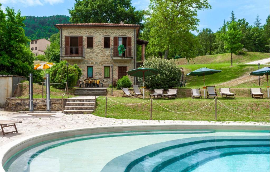 a pool in front of a house with chairs and umbrellas at Valguerriera 4 - Casale in Apecchio