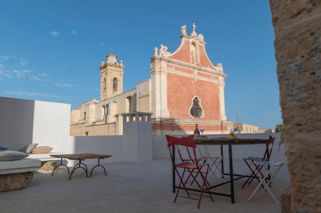 a patio with chairs and a table and a church at Palazzo Pati in Tiggiano