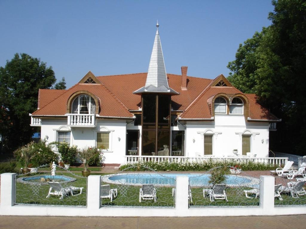 une grande maison blanche avec une église à la flèche dans l'établissement Kings Pension, à Gyenesdiás
