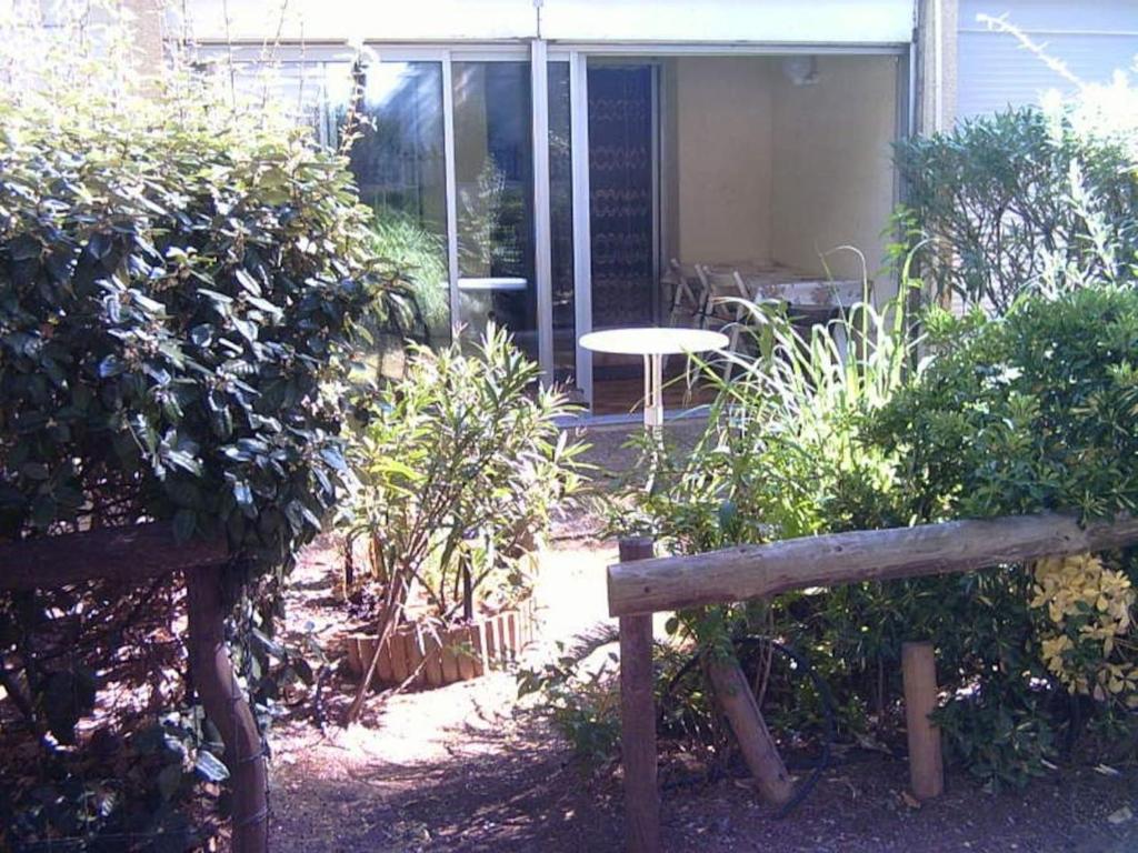 un banc en bois assis devant une maison dans l'établissement Studio avec jardin, piscine, sauna, proche de la mer et du village naturiste, au Cap d'Agde