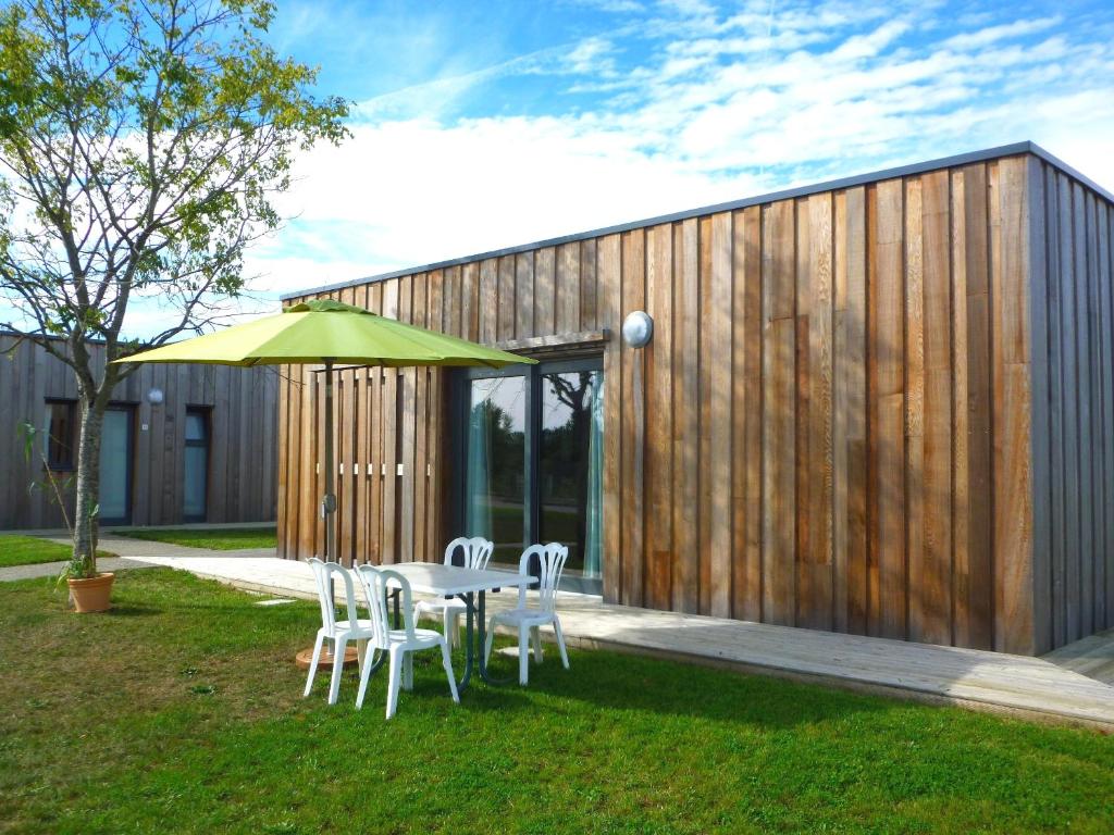 une table avec des chaises et un parasol devant un bâtiment dans l'établissement Domaine d'Ariane, à Mondonville