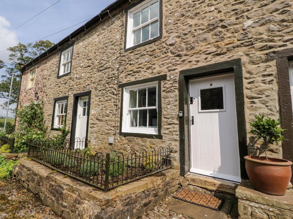 a stone house with a white door and a plant at 9 Bell Busk in Skipton