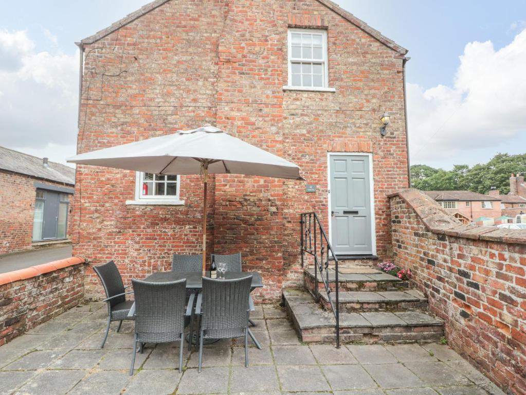 a table with an umbrella in front of a brick building at Wolds Way in Bainton