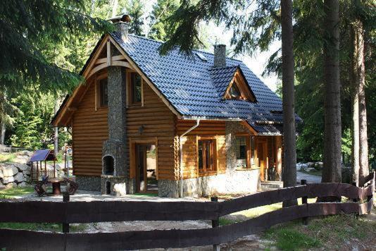une maison en bois avec une clôture devant elle dans l'établissement Domek Letniskowy Leśna Chata, à Szklarska Poręba