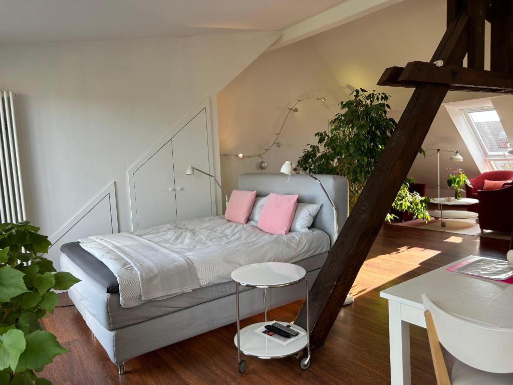 Un dormitorio con una cama con almohadas rosas y una mesa. en Dachstudio im Geteviertel - citynah, en Bremen