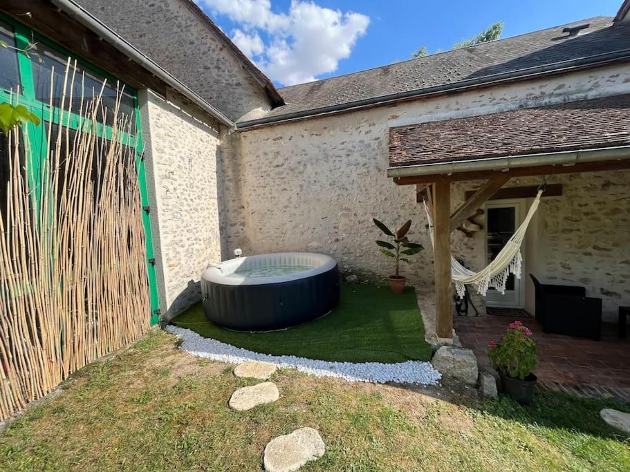 a backyard with a large tub in the yard at Gîte à la campagne et son jacuzzi privatif 