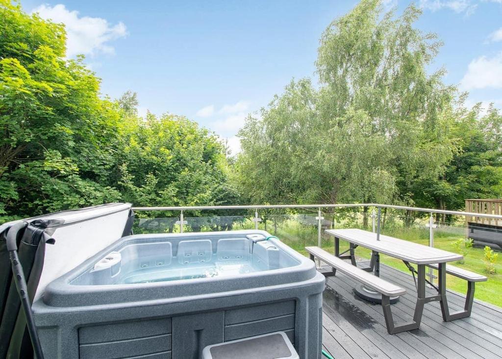 Riverview Holiday Park في Newcastleton: يوجد حوض استحمام ساخن على السطح مع طاولة نزهة
