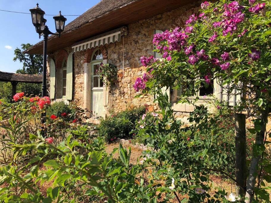 ein Steinhaus mit Blumen davor in der Unterkunft Le Domaine de la Cloche in Saint Pavace