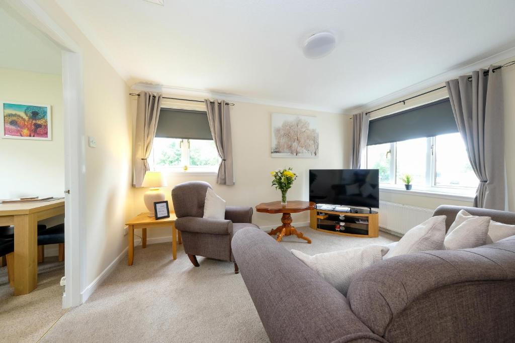 a living room with a couch and a tv at Pure Apartments Commuter- Dunfermline South in Fife