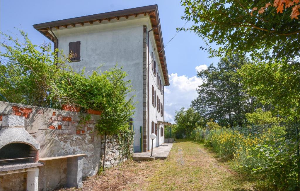 una casa bianca con un muro di pietra accanto a una strada di Pet Friendly Home In Bergotto With Outdoor Swimming Pool a Roccaprebalza