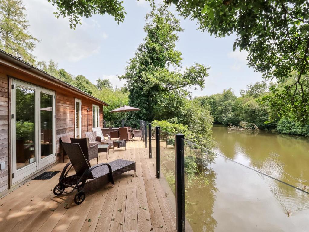 een houten terras met een bank en stoelen naast een rivier bij 6 Water's Edge in Looe