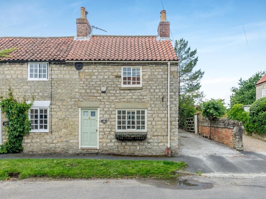 una casa de piedra con techo rojo en Maple Cottage, en Slingsby