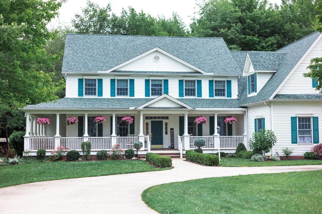 a house with a blue roof and pink flowers at The Inn at Woodsong Acres in Conneaut